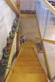 Dřevěné schody lemuje moderní drátěné zábradlí, jež odděluje místnost nahoře